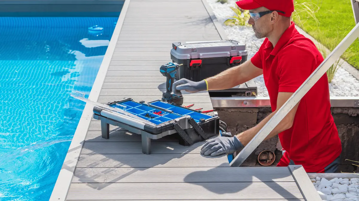 A pool technician installing equipment beside a pool