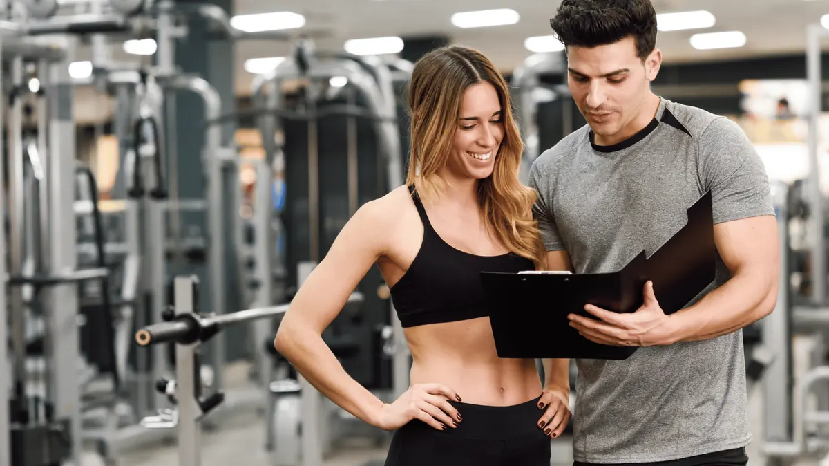 A personal trainer reviewing a plan with a client in a gym
