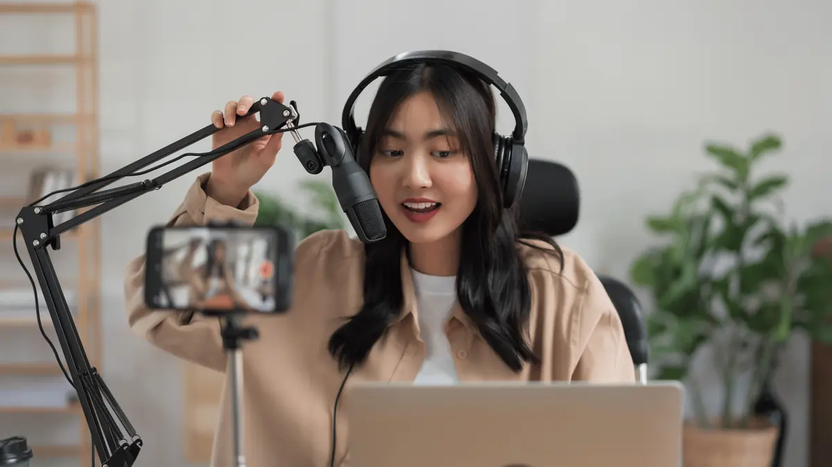 A content creator recording at a desk with a microphone and phone